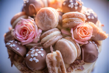 Close up of a delicious cake decorated with macarons, chocolate and roses, ready to be served during a party