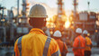 © MD Media - Group of construction workers wearing orange safety jackets and yellow hard hats, standing in front of an industrial building under construction. manager leading a team of construction professionals