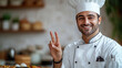© Niks Ads - A smiling chef in a white uniform is holding up his hands in a peace sign