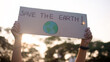 © ChayTee - Go green people young woman hand raised showing save the earth planet world care banner poster sign in city nature tree sun light sunset. Plastic free issues Protect future asian hope net zero waste