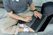 © Seventyfour - Top view of unrecognizable businessman typing on laptop keyboard while sitting on pavement working remotely outside in city street, copy space