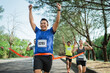 © Odua Images - asian marathon participant crossing finish line with hands up gesture