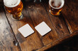 © uniyok - Empty beer coasters mockup on wooden table. Top view of beer coasters set. Blurred bar background.