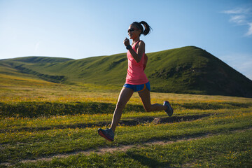 Poster - Fitness woman runner running at flowering grassland mountain top