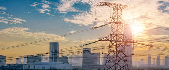 Wall Mural - Aerial shot of high voltage electricity tower and city skyline at sunset