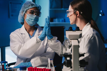 Wall Mural - team of biochemical research scientists working with a microscope for vaccine development