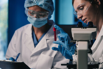 Wall Mural - team of biochemical research scientists working with a microscope for vaccine development