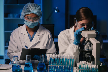 Wall Mural - team of biochemical research scientists working with a microscope for vaccine development