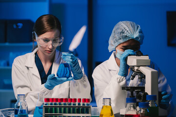 Wall Mural - team of biochemical research scientists working with a microscope for vaccine development