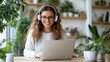 © Pinklife - A woman with glasses and headphones smiles at her laptop inside a cozy plant-filled room, suggesting productivity and relaxation in a natural environment.