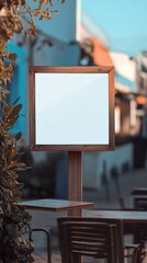 Blank wooden framed sign stands in foreground of blurred urban scene, autumn leaves frame edge, warm tones contrast with blue sky, copy space.