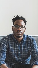 Poster - A man with glasses and a beard is sitting on a couch