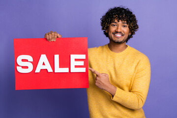 Sticker - Photo of positive man wear stylish yellow jumper arms hold red placard recommend sale offer isolated on purple color background