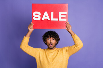 Poster - Photo of shocked man wear trendy yellow clothes arms above head hold red placard sale isolated on purple color background