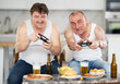 © caftor - Two adult men playing video game console