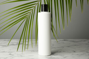 Wall Mural - Bottle of shampoo on white marble table against grey background