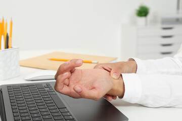 Poster - Carpal tunnel syndrome. Woman suffering from pain in wrist at desk indoors, closeup