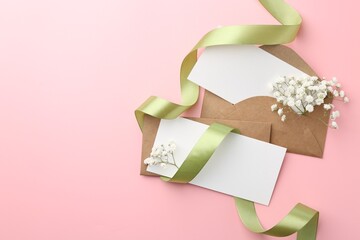 Wall Mural - Blank cards, envelopes, ribbon and gypsophila flowers on pink background, flat lay. Space for text