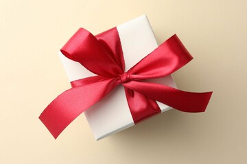 Wall Mural - Beautiful gift box with red bow on beige background, top view