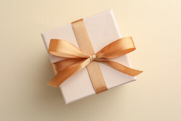 Poster - Beautiful gift box with golden bow on beige background, top view