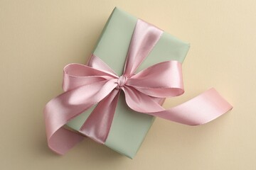 Wall Mural - Beautiful gift box with pink bow on beige background, top view