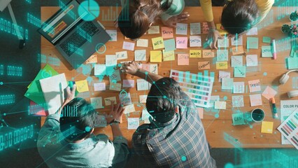 Top down view of business team with casual outfit looking laptop screen and sharing idea. Aerial view of manager works and checking color palette at table with statistic graph holographic. Symposium.