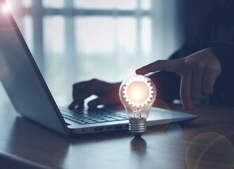 The idea of ​​inspiration from online technology. innovation idea concept.with a light bulb And there is a gear icon in it And he is using a notebook computer.