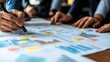 © rookielion - Close-up of hands collaborating on business charts and data analysis, emphasizing teamwork and strategic planning.