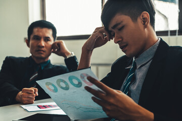 Unhappy business manager and young businessman partner in meeting room at the office. They are under stress because of bad financial document report. Company crisis concept. uds