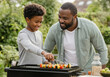 © Running opossum - Happy father and son grilling vegetable skewers on a barbecue in the backyard
