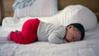 © Marco - Peaceful newborn baby sleeping on a bed, dressed in cozy red pants, capturing a serene and restful moment of early life, surrounded by the soft comfort of a home environment