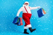 © deagreez - Full length profile side photo of crazy modern white grey hair bearded santa claus go shopping buy x-mas christmas bags wear red suspenders overalls boots isolated blue color background
