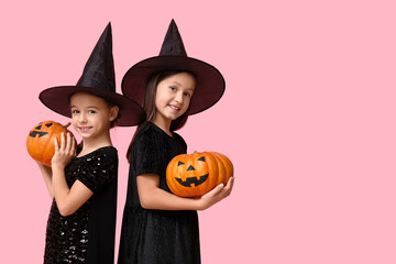 Wall Mural - Cute little girls dressed for Halloween as witches with pumpkins on pink background