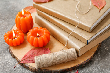 Wall Mural - Composition with tray, stack of books, candles and autumn leaves on grunge background, closeup