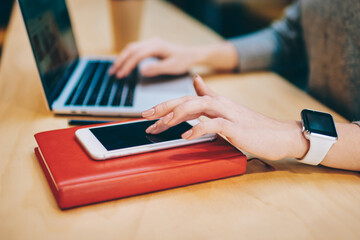 Fototapete - Cropped image of female hand searching sms message on new smartphone gadget standing on red textbook for education, skilled remote worker checking notification received on modern mobile phone