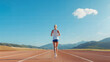 © filmanana - Woman running on track in scenic mountain landscape under blue sky