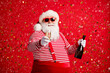 © deagreez - Congratulations. Photo of old man grey beard hold bottle champagne glass make toast wear santa x-mas costume suspenders sunglass striped shirt cap isolated red color background