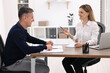 © New Africa - Banker working with client at wooden table in office