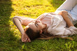 © New Africa - Woman resting on green lawn in park