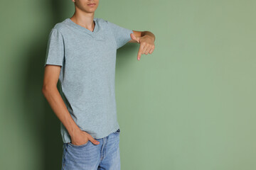 Poster - Teenage boy wearing light grey t-shirt on green background, closeup. Space for text