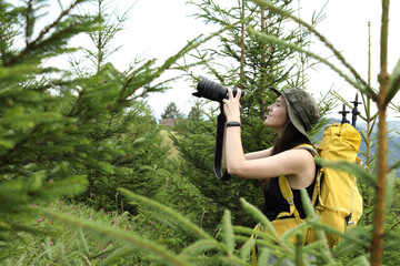 Canvas Print - Young hiker with backpack and camera in forest, space for text