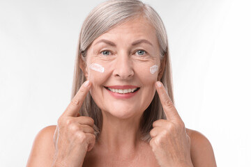 Canvas Print - Senior woman with face cream on white background