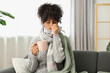 © New Africa - Cold symptom. Young woman with tissue and cup of hot drink at home