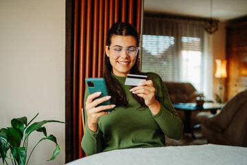 Young caucasian woman shopping online on smartphone using credit card	