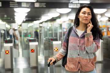 Asian woman passing through ticket gates in a public transportation station