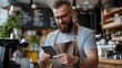 © maesarin - Customer using a smartphone to complete a digital payment with a barista s handheld device in a modern cafe showcasing mobile payment technology