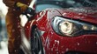 © itykhonova - Close-up of a worker washing a red car with a focus on the headlights, symbolizing car maintenance, cleanliness, and automotive care. Concept of vehicle care, detailing, and cleanliness