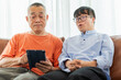 © JU.STOCKER - Asian Senior man and grandson using tablet smartphone doing a video call in living room, Grandparents and grandson having fun together at home