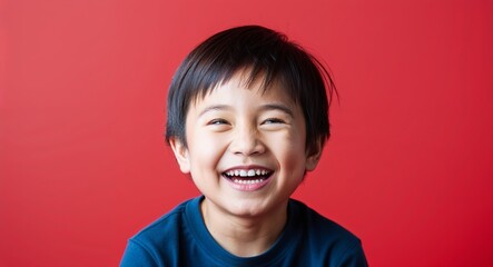 Child Asian boy with bright smile and short straight hair laughing warm red background