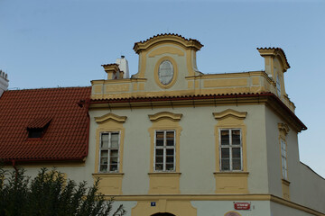 There stands a large, impressive white building that features a distinctive red tiled roof, creating a striking visual appearance against the sky